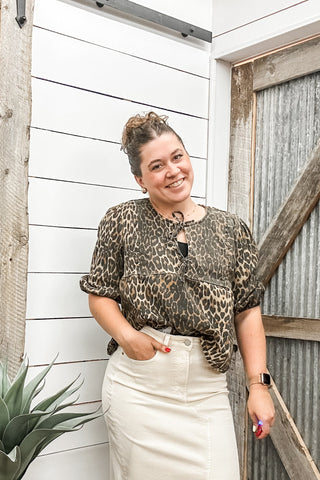 Woman wearing a leopard print top and white skirt.